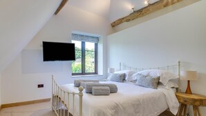 Una camera da letto con un letto, una televisione a parete, una finestra con vista e un soffitto con travi in legno.
