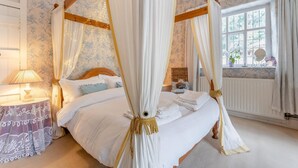 A four-poster canopy bed with white linens, a bedside table with a lamp, and a window with curtains. - 2 Bed in Knighton (oc-t32800) (Whitton)