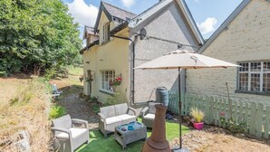 A house with a patio area featuring outdoor furniture, a large umbrella, and a decorative metal vase. - 2 Bed in Knighton (oc-t32800) (Whitton)