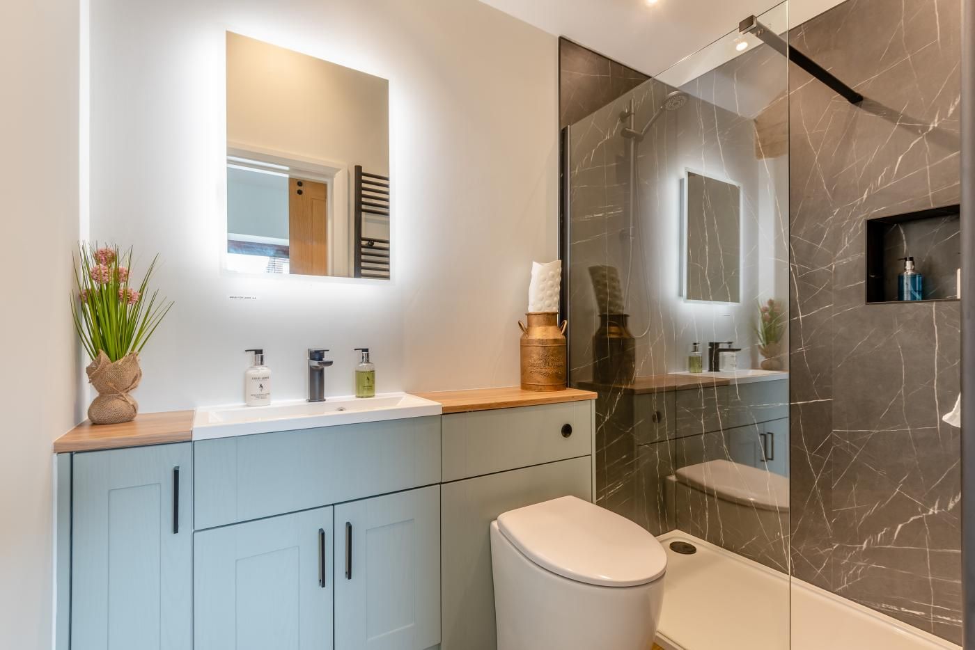 A modern bathroom with a glass shower enclosure, a vanity with a mirror, and a toilet.