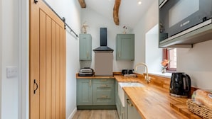 A compact kitchen with wooden cabinets, a built-in Bosch oven, and a sink with a gold faucet. - 1 Bed in Wetheral (oc-r32933) (Great)