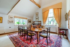 A dining area with a wooden table and chairs, a patterned rug, and a window with curtains. - 5 Bed in Magham Down (oc-sx942) (Hailsham)