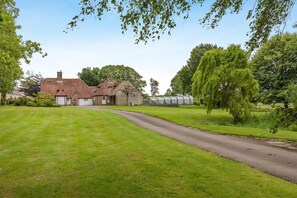 A rural property with a large house, a greenhouse, and a well-maintained lawn. - 5 Bed in Magham Down (oc-sx942) (Hailsham)