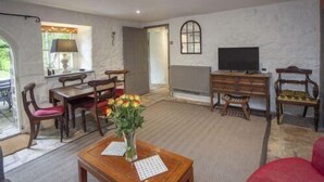 A spacious living room with a wooden dining table, chairs, a television, and a fireplace. - 2 Bed in Bath (oc-bhr35) (Bath)