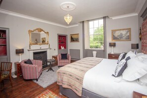 Ein Schlafzimmer mit einem großen Bett, einem Kamin, einer Chandelüster und einem Fenster mit Blick.