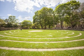 Ein kreisförmiger Garten mit einem zentralen Brunnen, umgeben von einem gepflasterten Weg.