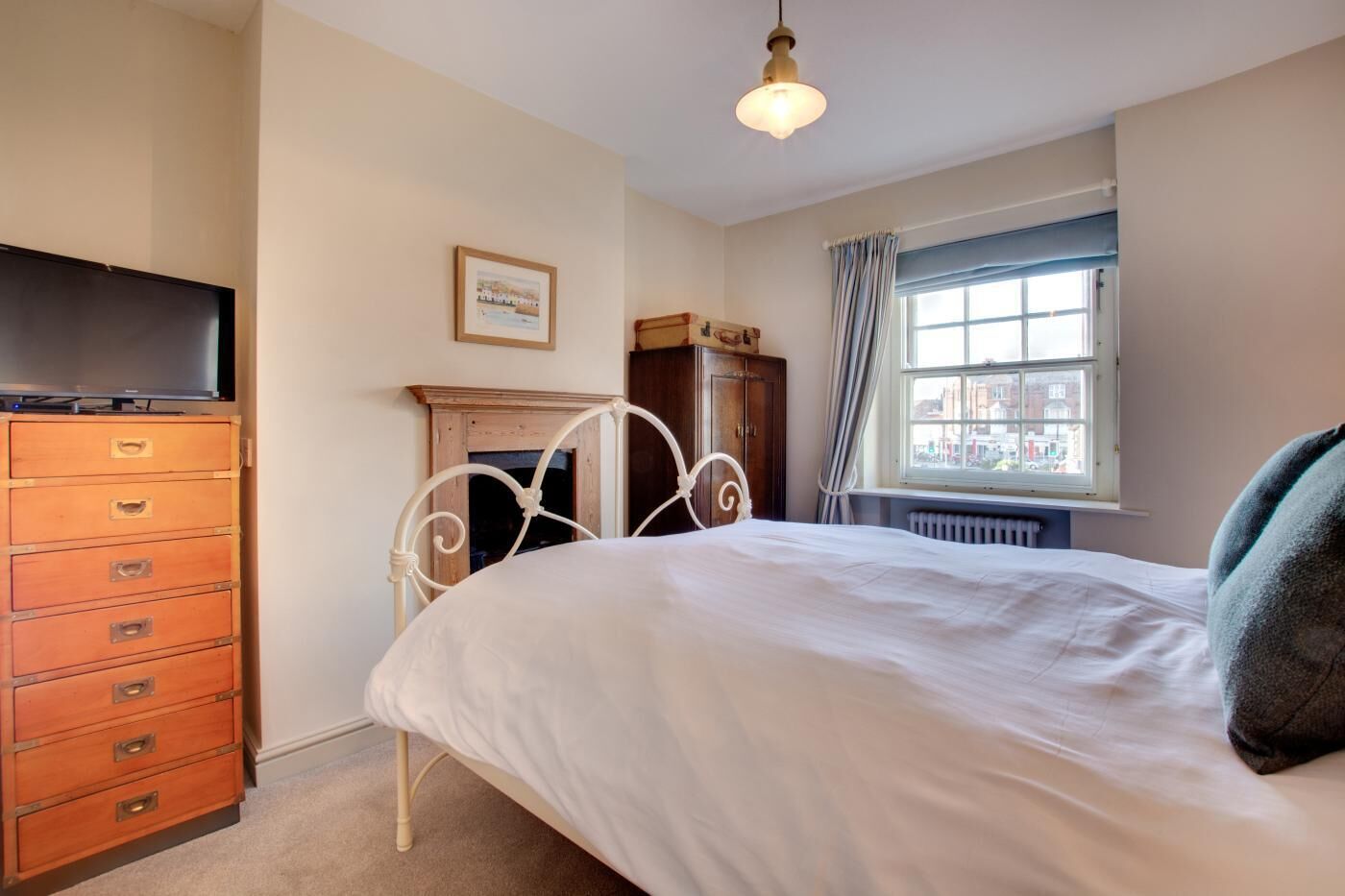 A bedroom with a bed, dresser, and a window with a view.