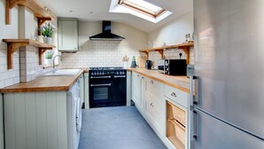 A compact kitchen with a skylight, built-in oven, and wooden shelves. - 3 Bed in Cromer (oc-1670) (Cromer)