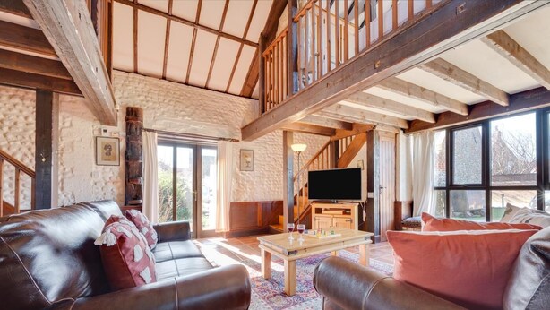 A spacious living room with a leather sofa, a wooden coffee table, and a television. - 2 Bed in Bacton (oc-712) (Bacton)