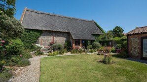 A traditional thatched-roof house with a well-maintained garden and a clear blue sky. - 2 Bed in Bacton (oc-712) (Bacton)