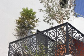 A geometric metal fence, a white wall, and a tree with green foliage. - Casa Mestiza (Guadalajara)