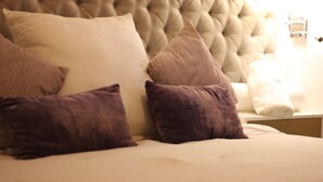 A bed with a tufted headboard, multiple pillows, and a neatly made white bedspread. - Casa Mestiza (Guadalajara)