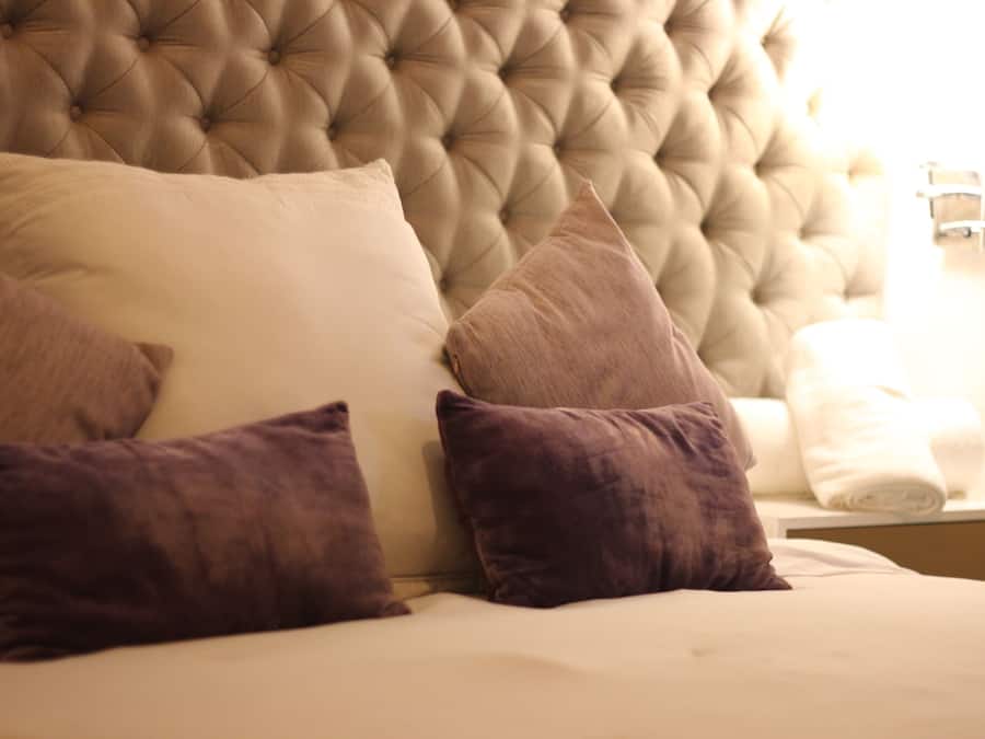 A bed with a tufted headboard, multiple pillows, and a neatly made white bedspread.