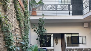 A multi-level courtyard with a stone wall, potted plants, and a tiled floor. - Casa Mestiza (Guadalajara)