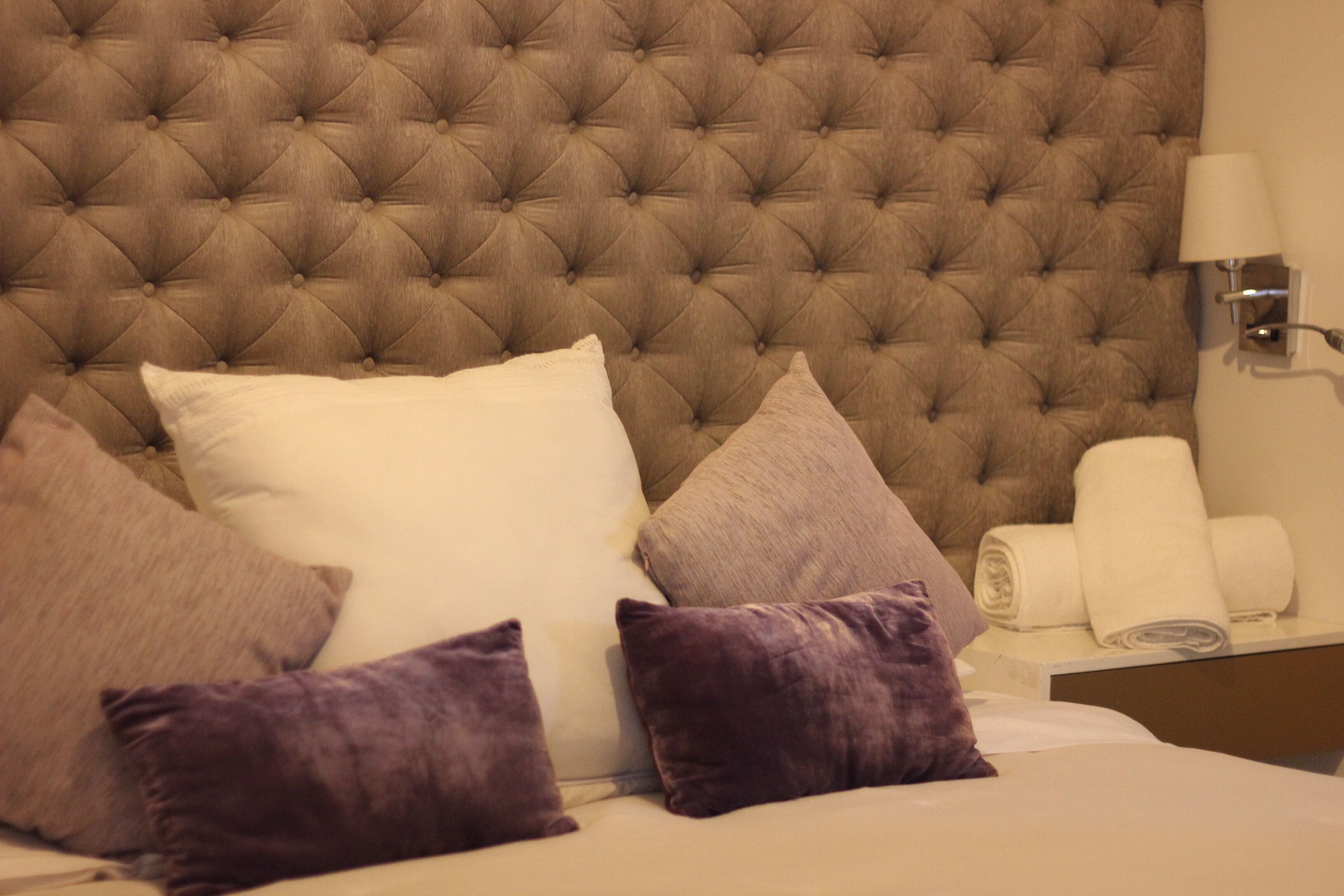 A bed with a tufted headboard, multiple pillows, and a neatly made bed.