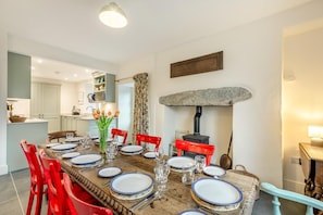 A dining area with a wooden table set for four, red chairs, and a vase of tulips. - 5 Bed in Ulpha (oc-b32731) (Ulpha)