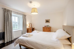 A bedroom with a bed, bedside table, dresser, and a window with curtains. - 5 Bed in Ulpha (oc-b32731) (Ulpha)