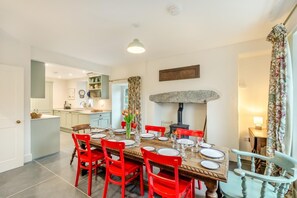 A dining area with a wooden table, red chairs, and a stone fireplace.