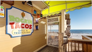 A beachside restaurant named 'Rockin' Tacos Grill & Tequila Bar' with a view of the ocean.