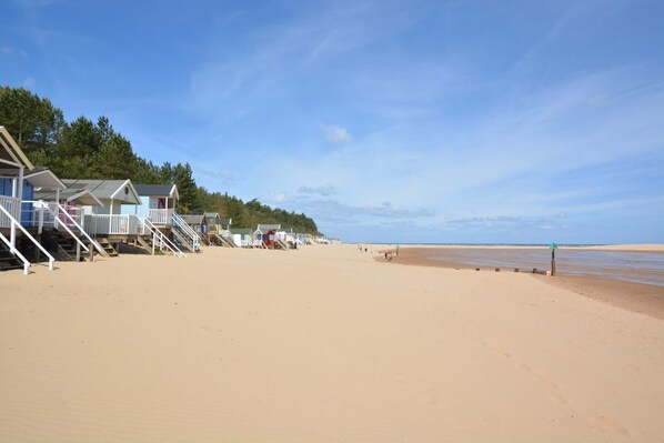 A beach with wooden beach huts and a clear sky.