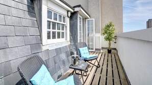 A balcony with two wicker chairs, a small table with a glass, and a potted plant. - 1 Bed in Brighton (oc-bbnest) (Hove)