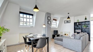 A modern loft apartment with a dining area, a gray sofa, and a black dining table. - 1 Bed in Brighton (oc-bbnest) (Hove)