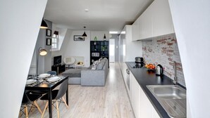 A modern kitchen with a black countertop, a stainless steel sink, and a brick backsplash. - 1 Bed in Brighton (oc-bbnest) (Hove)