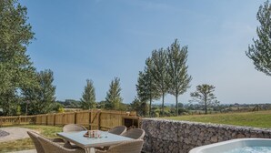 Une terrasse extérieure avec une table et des chaises, un mur en pierre et un jacuzzi.