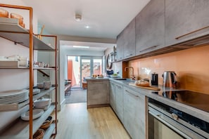 A modern kitchen with a central island, stainless steel appliances, and a view to a patio area. - 3 Bed in Brighton (oc-bbcorn) (Brighton)