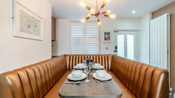 Un comedor con una disposición de asientos tipo cabina, una mesa de madera preparada para cuatro personas y una lámpara en el techo.