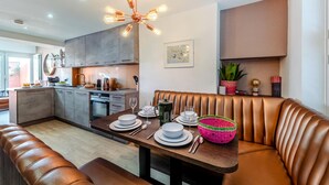 Una cocina moderna con comedor, que cuenta con una isla central, horno empotrado y lámpara en el techo.