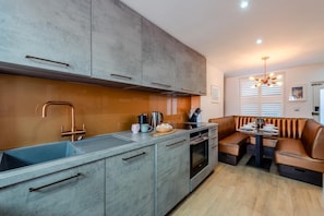 A modern kitchen with grey cabinets, a stainless steel sink, and a built-in oven.