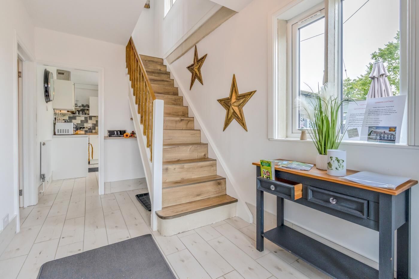 A modern interior with a wooden staircase, a desk with a plant, and a window with a view.