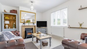A cozy living room with a fireplace, leather sofas, a dining table, and a TV. - 3 Bed in Forden (oc-c30173) (Forden)