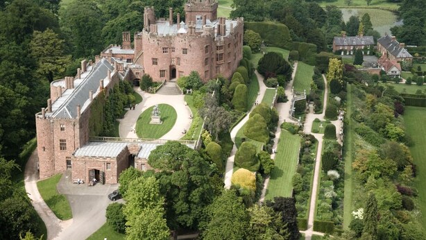 A large castle with a central courtyard, surrounded by manicured gardens and a golf course. - 3 Bed in Forden (oc-c30173) (Forden)