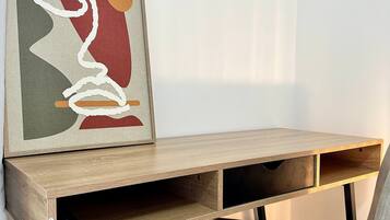Een houten bureau met een comfortabele stoel, een lijst met abstract schilderij en een effen muur.