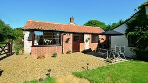 A single-story house with a tiled roof, a brick exterior, and a small front yard with gravel and potted plants. - 1 Bed in Banningham (oc-1389) (Banningham)