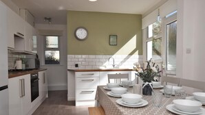 Una cucina moderna con mobili bianchi, un piano di lavoro in legno e un'area pranzo con tovaglia fantasia.