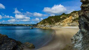 Una spiaggia costiera con acqua cristallina, una riva sabbiosa e scogliere rocciose.