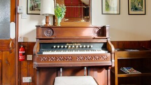 A piano with a bench in a room with wooden walls and a fire extinguisher on the wall. - 1 Bed in Banningham (oc-564) (Banningham)