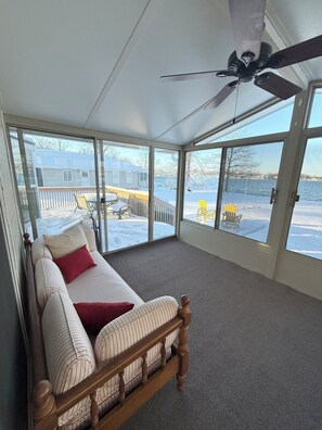 A bedroom with a bed, a ceiling fan, and large windows offering a view of a snowy deck and a lake. - Lakefront Cottage- Newly Renovated 3BR Retreat (Fremont)