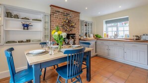A kitchen with a brick fireplace, white cabinets, and blue chairs. - 2 Bed in East Brent (oc-k32780) (East Brent)