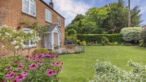 A brick house with a well-maintained lawn, a garden with pink flowers, and a wooden chair. - 2 Bed in East Brent (oc-k32780) (East Brent)
