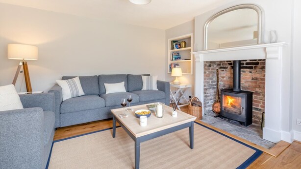 A cozy living room with a grey sofa, a coffee table with candles, and a fireplace. - 2 Bed in East Brent (oc-k32780) (East Brent)