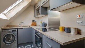 Cocina compacta con lavadora, microondas y hervidor.