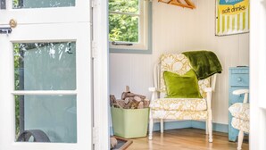 A cozy room with a white door, a patterned armchair with a green throw, a small green basket, and a blue dresser. - 1 Bed in Ashprington (oc-m32906) (Ashprington)
