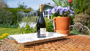 Une bouteille de vin, quatre verres et une plante en pot sur une table à l’extérieur.