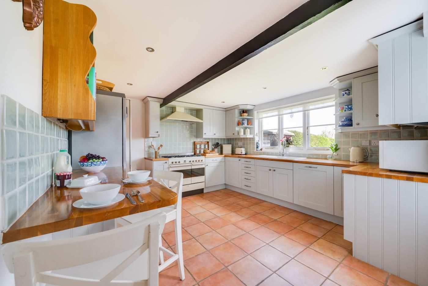A kitchen with white cabinets, a wooden countertop, and a tiled floor.
