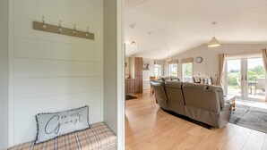 A cozy living room with a sofa, a bench with a cushion, and a wall-mounted coat rack.