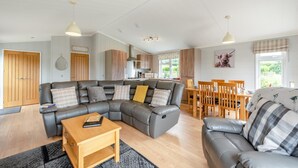 A modern living room with a sectional sofa, a wooden coffee table, and a dining area with wooden chairs and a table.